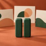 A green pause symbol stands in front of three cream display cards on a terracotta surface.